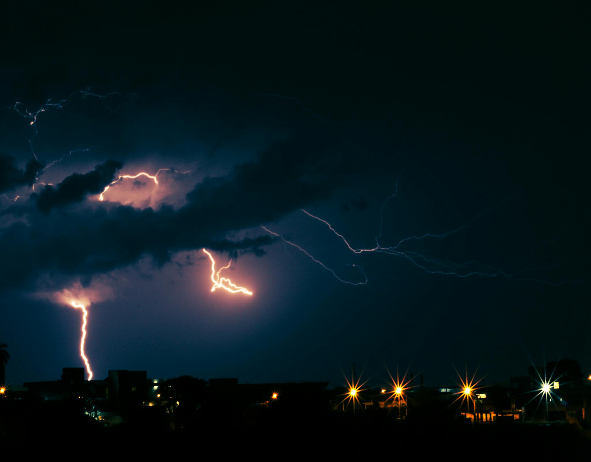 Striking lightning illuminates the dark sky over Belo Horizonte at night, capturing the energy of an urban thunderstorm.